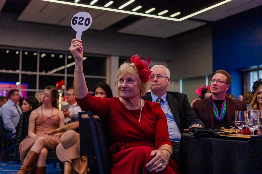 A guest in red raises bidding paddle number 620 during the paddle raise at the GiGi's Playhouse Indy gala.