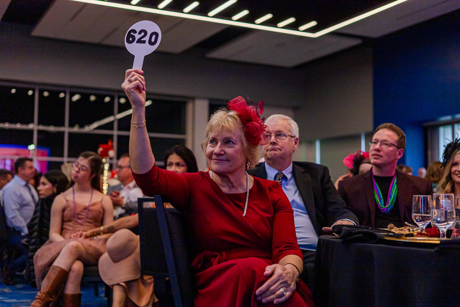 A donor raising her paddle during the paddle raise at a fundraising gala entertained by fundraiser magician Josh Weidner