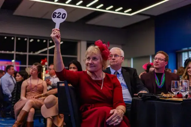 A donor raising her paddle during a fundraising gala in Los Angeles