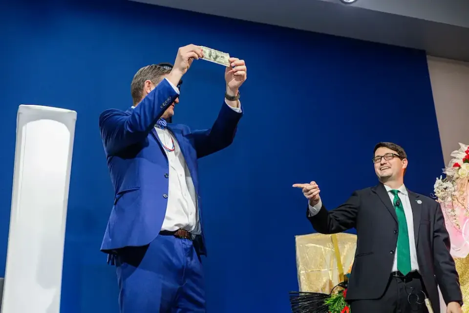 Denver magician Josh Weidner hosting an event from the stage with a volunteer